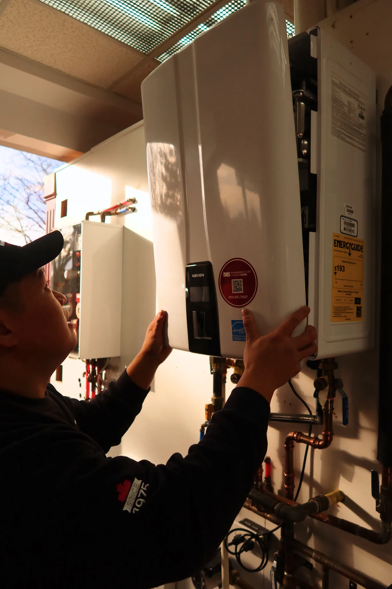 A technician installing a tankless water heater on a wall.