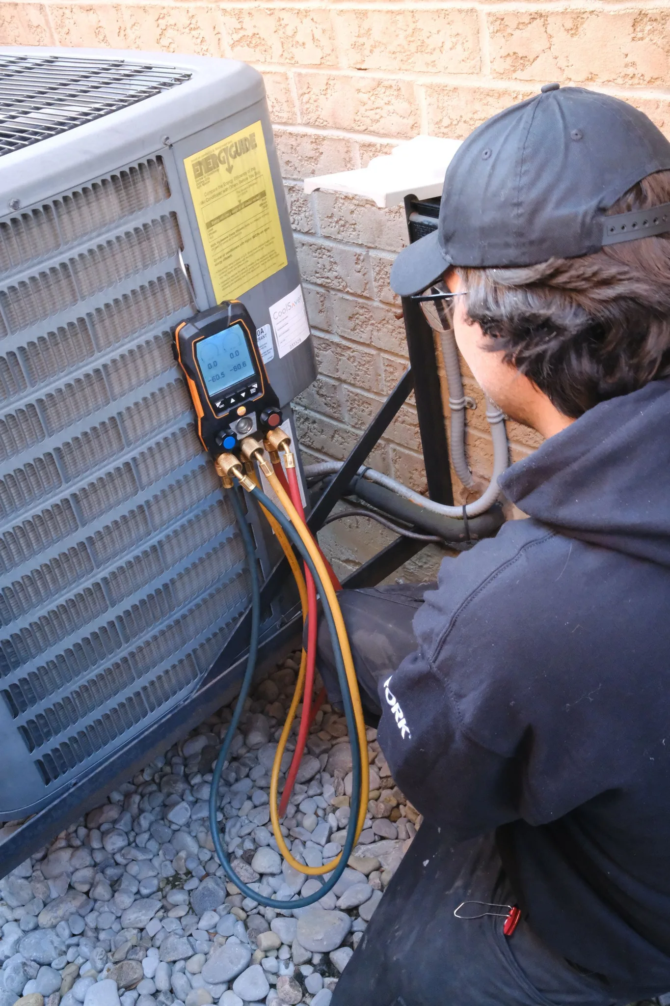 Technician checking HVAC unit pressure with a digital gauge.