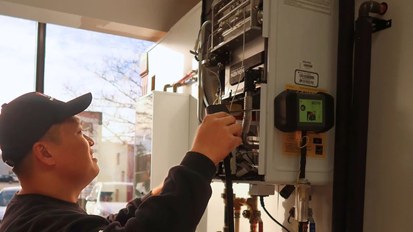 A technician servicing an HVAC unit indoors.