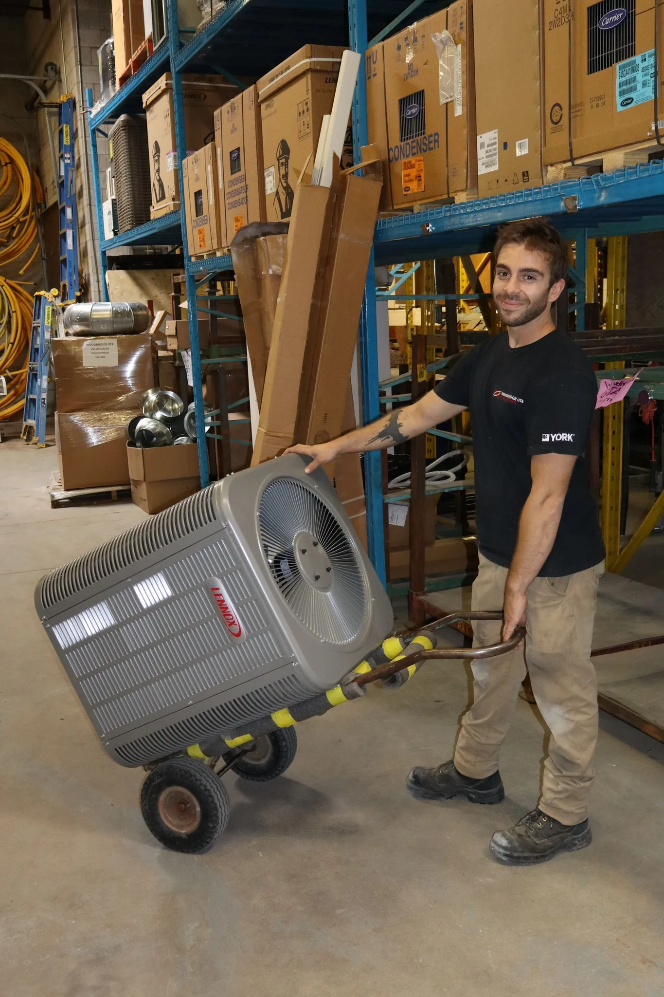 A technician moving an air conditioning unit in a warehouse.