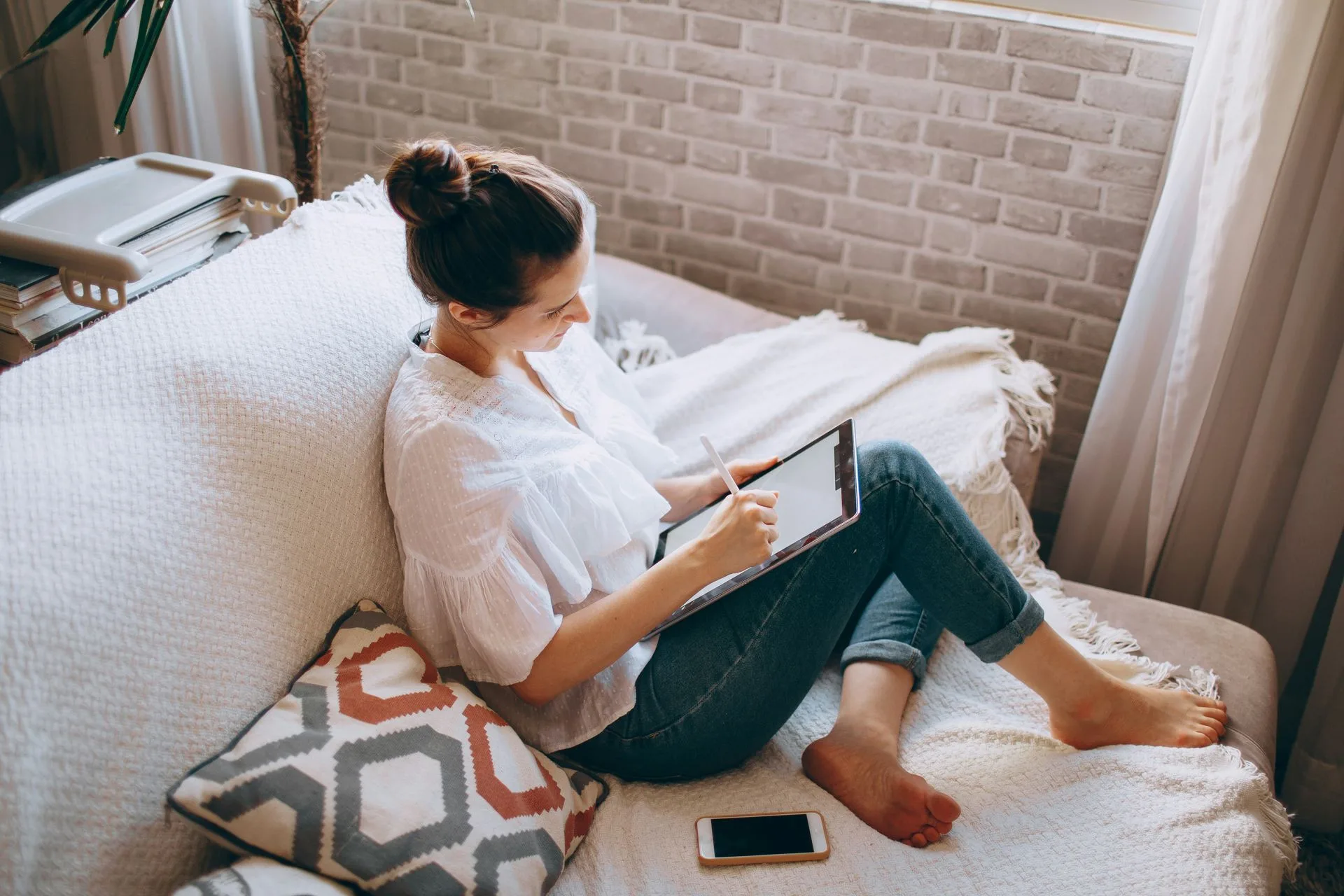 A woman using a tablet on a couch.
