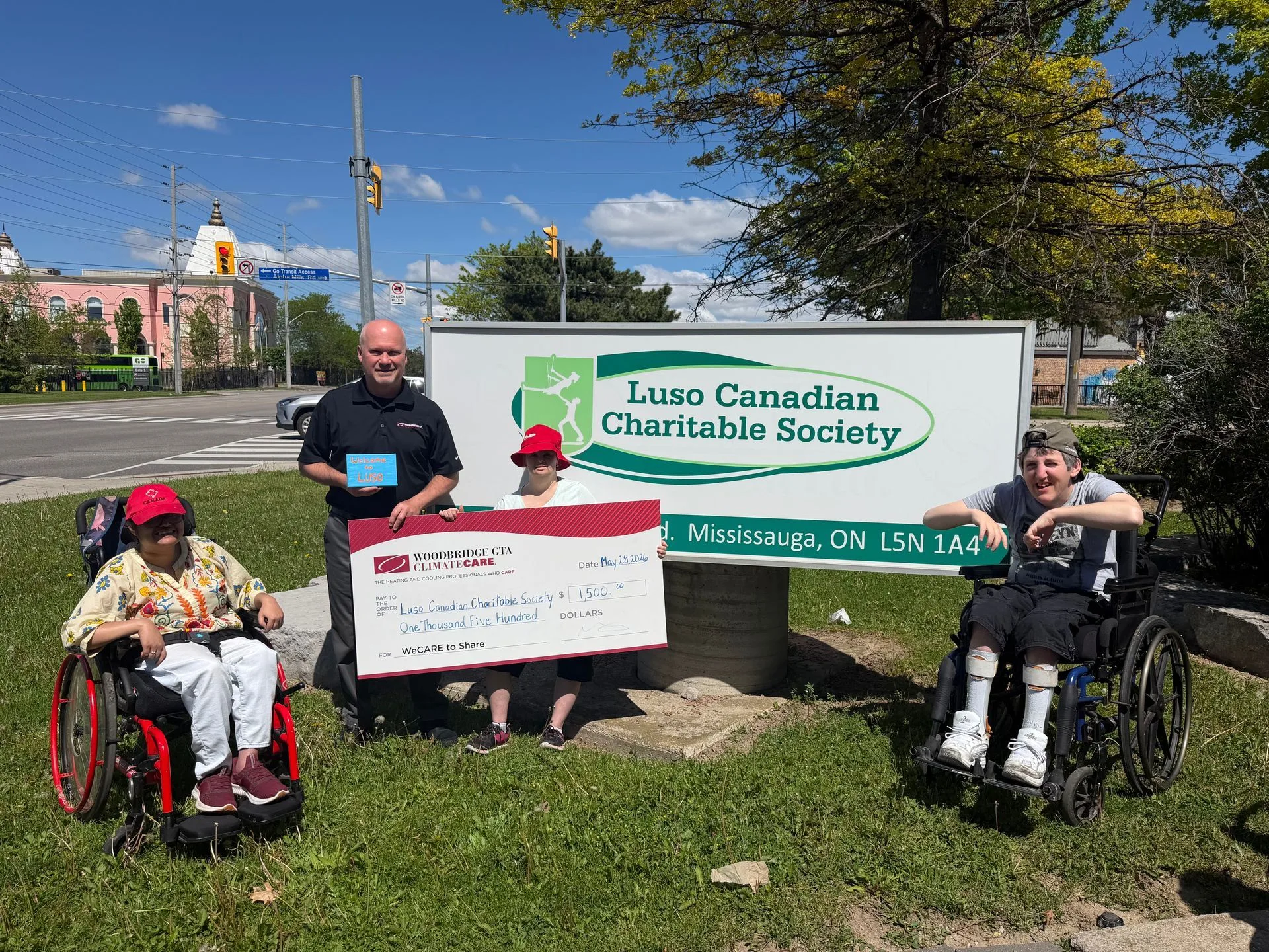 Group holding a check in front of Luso Canadian Charitable Society sign.