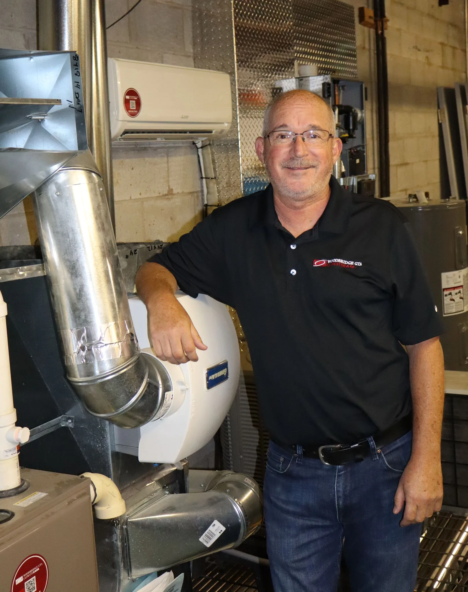 A technician standing by HVAC equipment in a workshop.