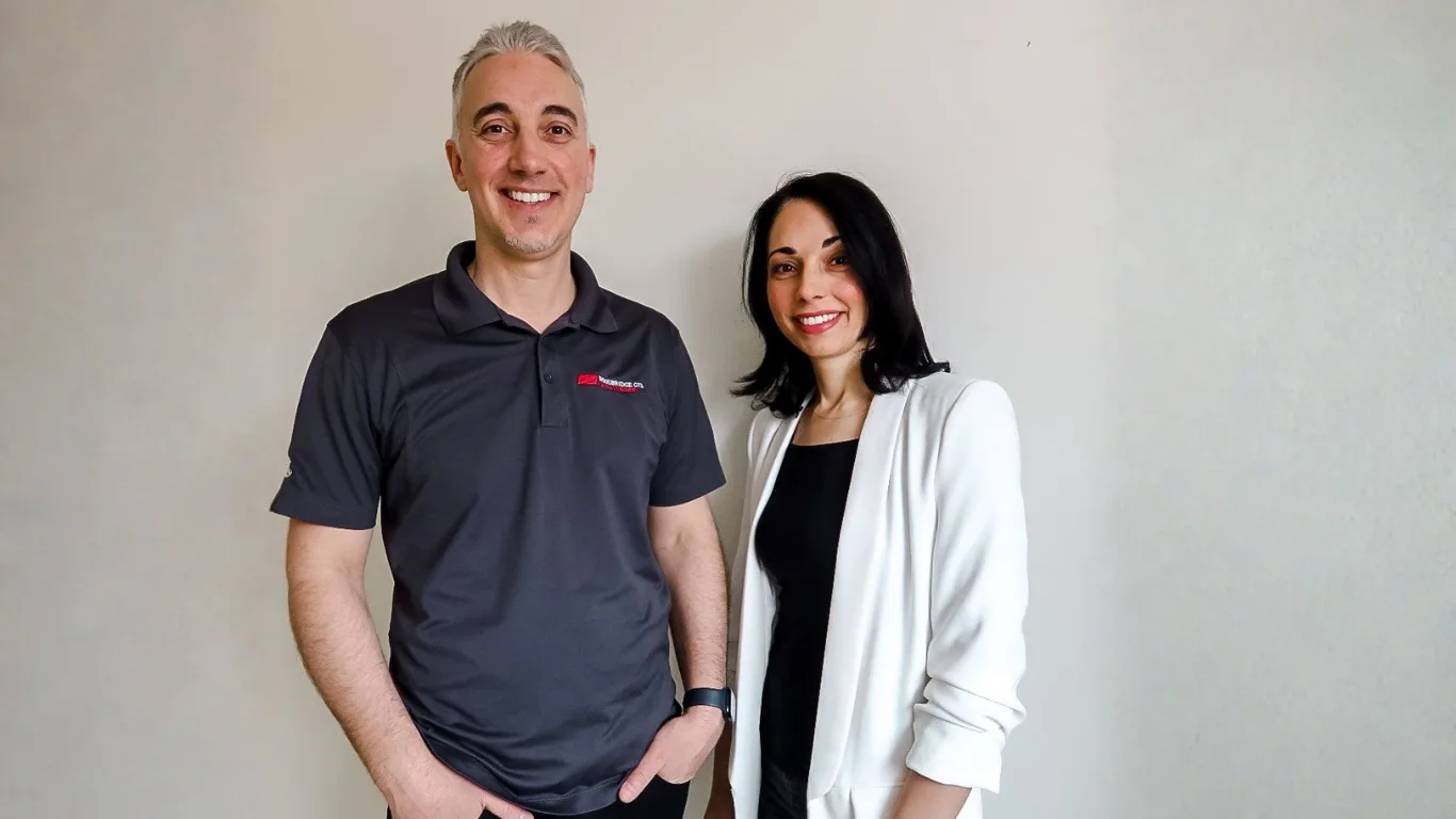 Two professionals posing together in casual attire.