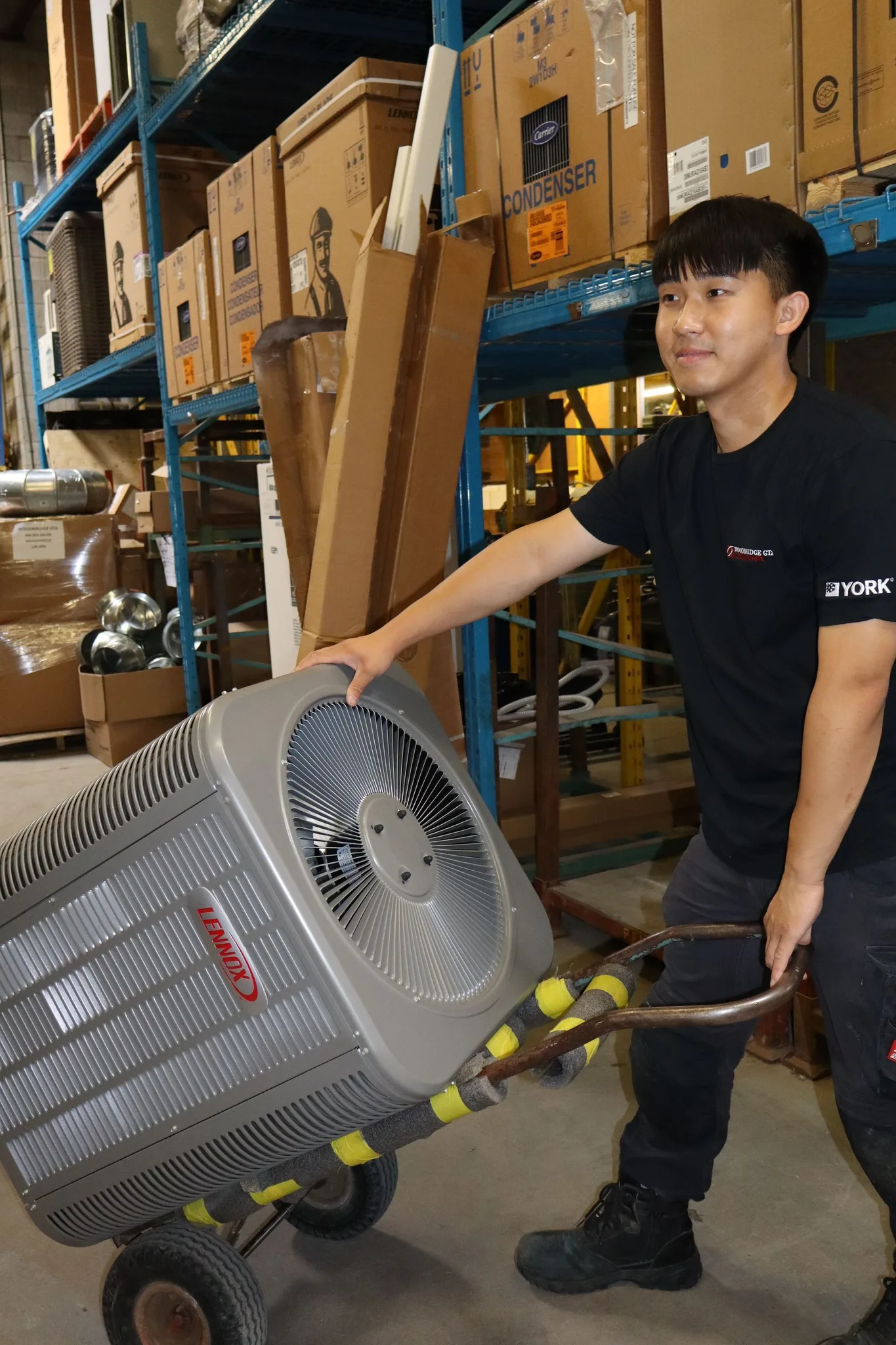 Technician moving an air conditioning unit in a warehouse.