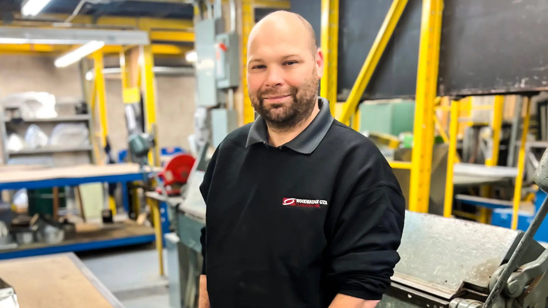 A man in a workshop wearing a branded sweatshirt.