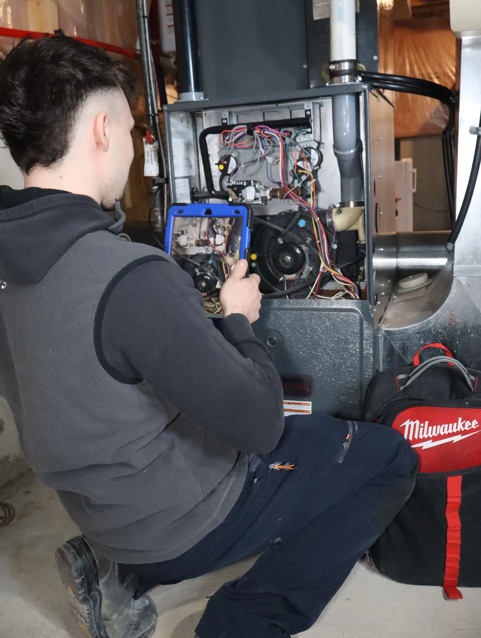 A technician inspecting a furnace with a tablet.