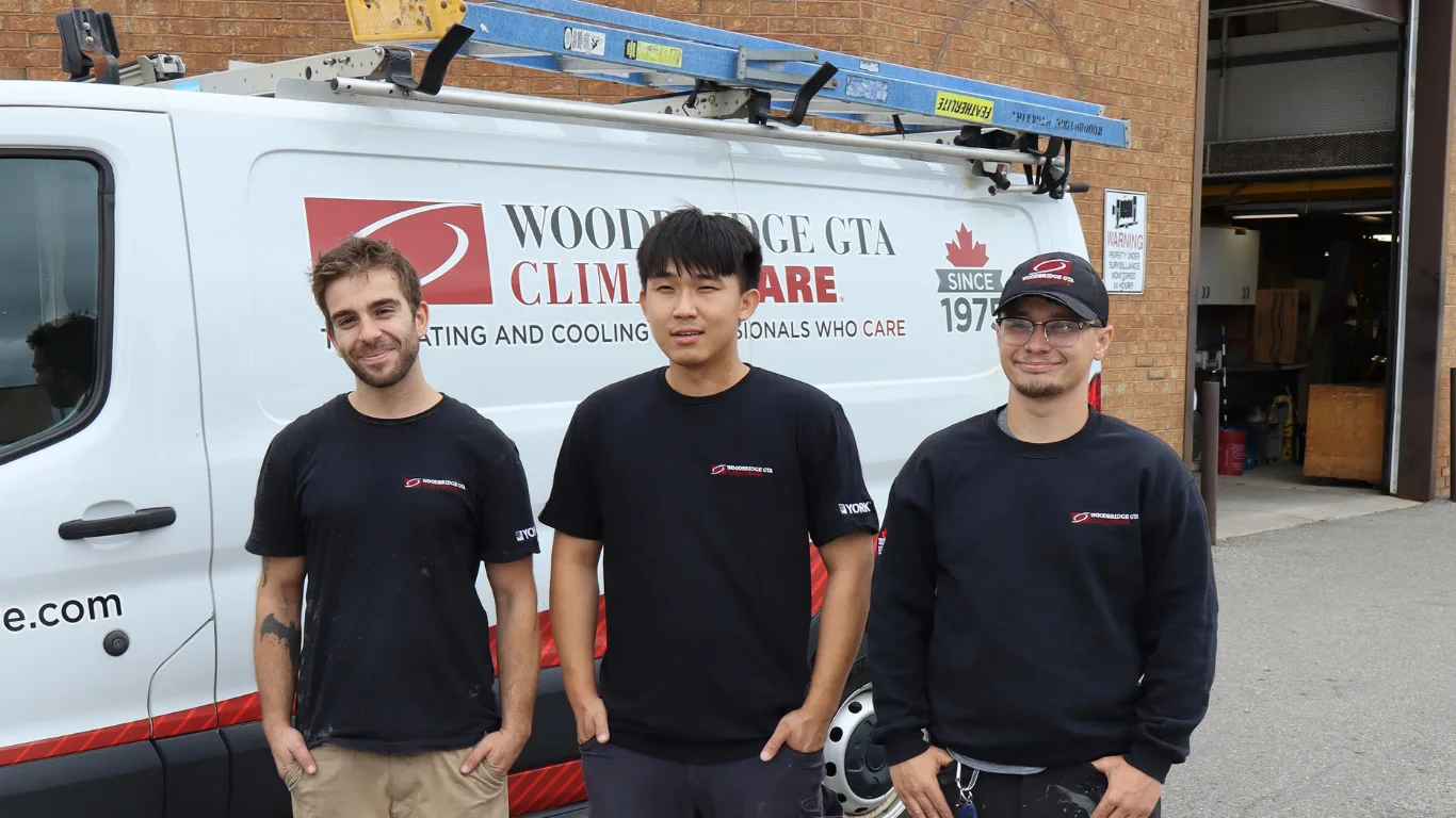 Three HVAC technicians in front of a service van.