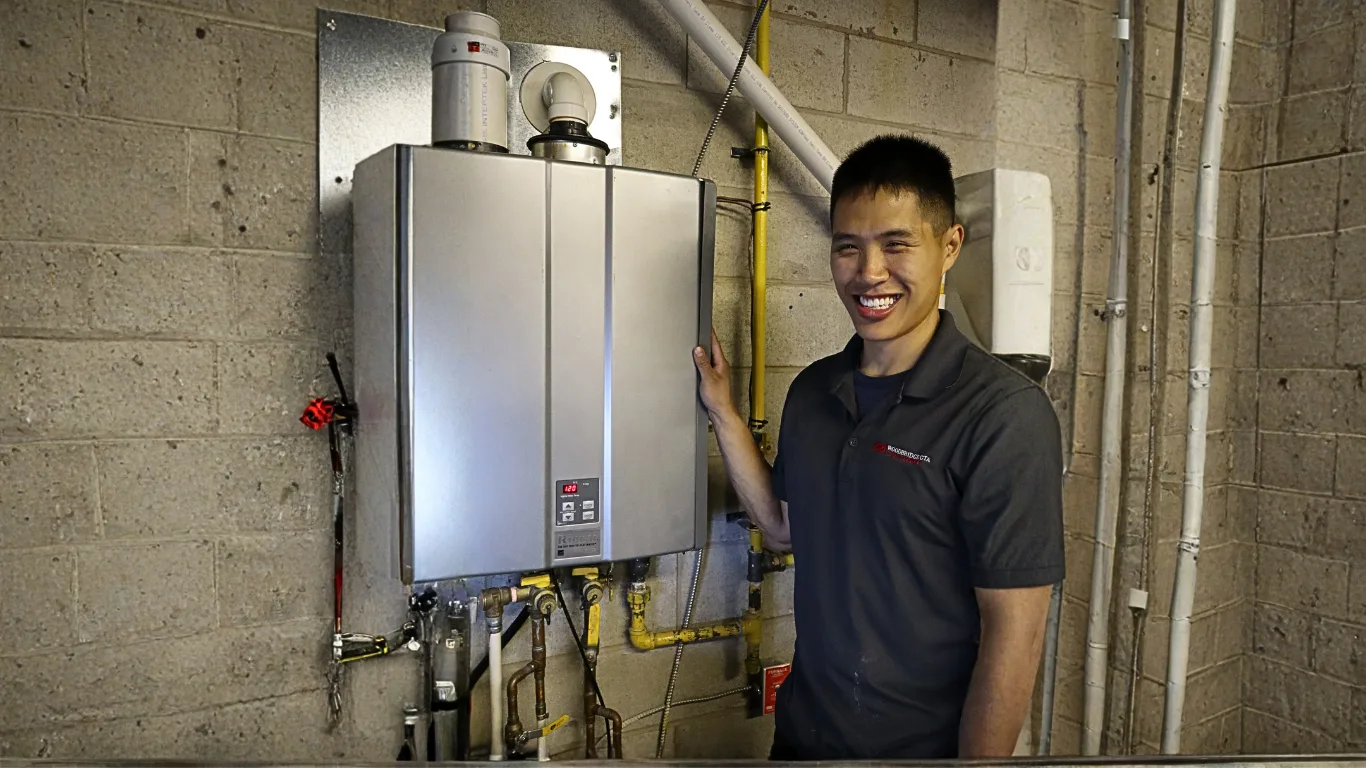 A technician smiles next to a tankless water heater.