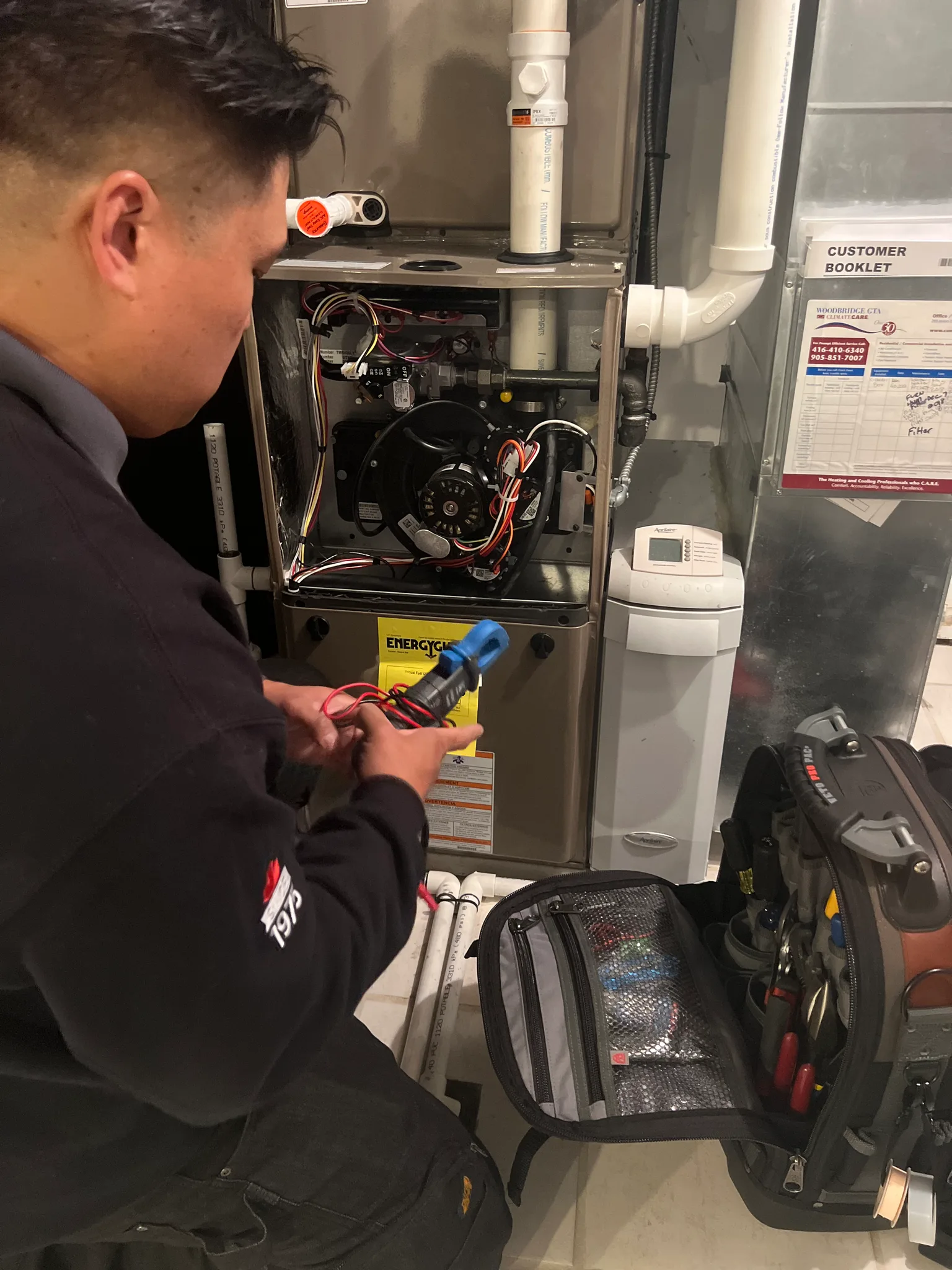 A technician inspecting a furnace in a utility room.