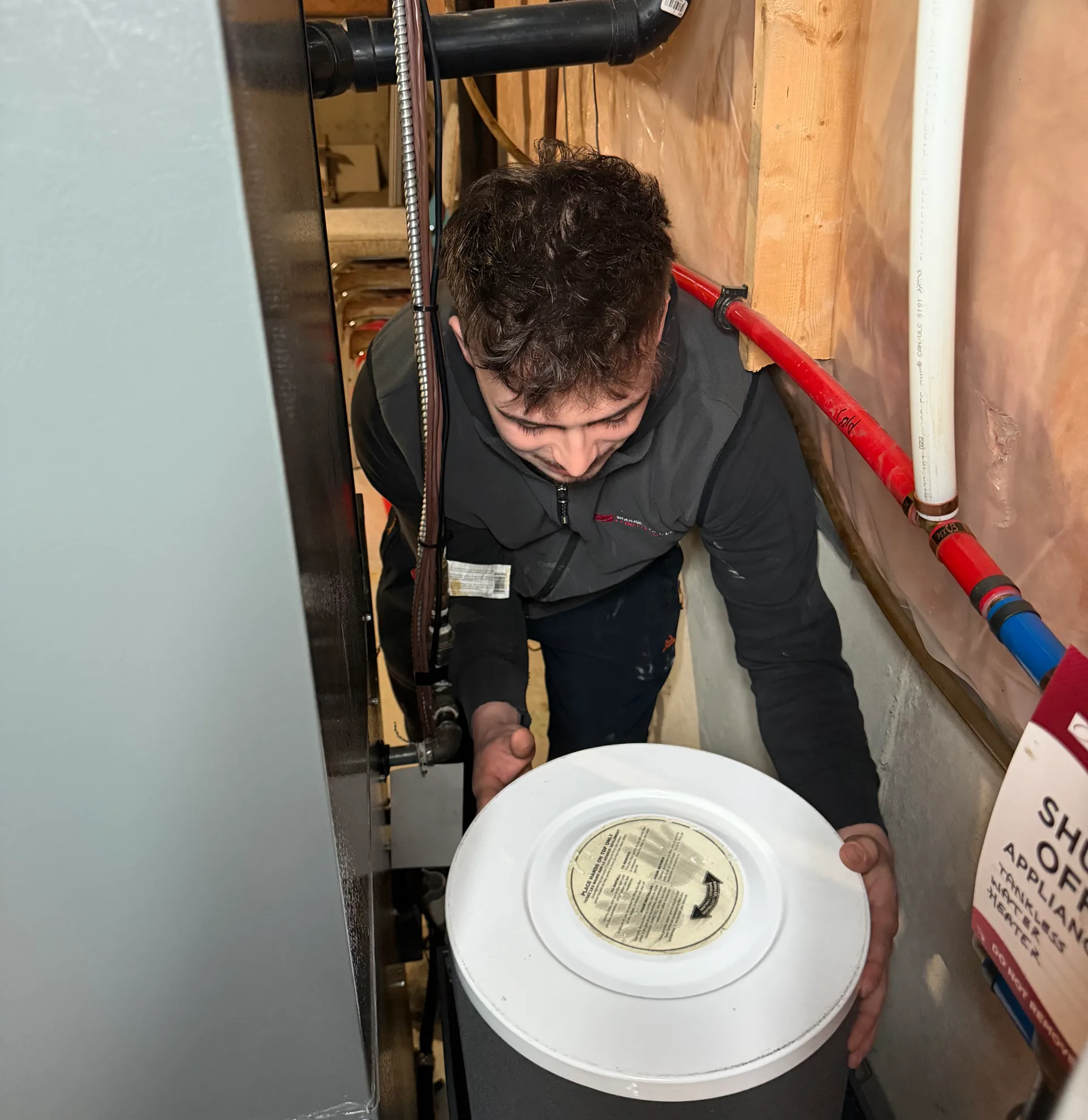 A technician installing an appliance component in a utility room.