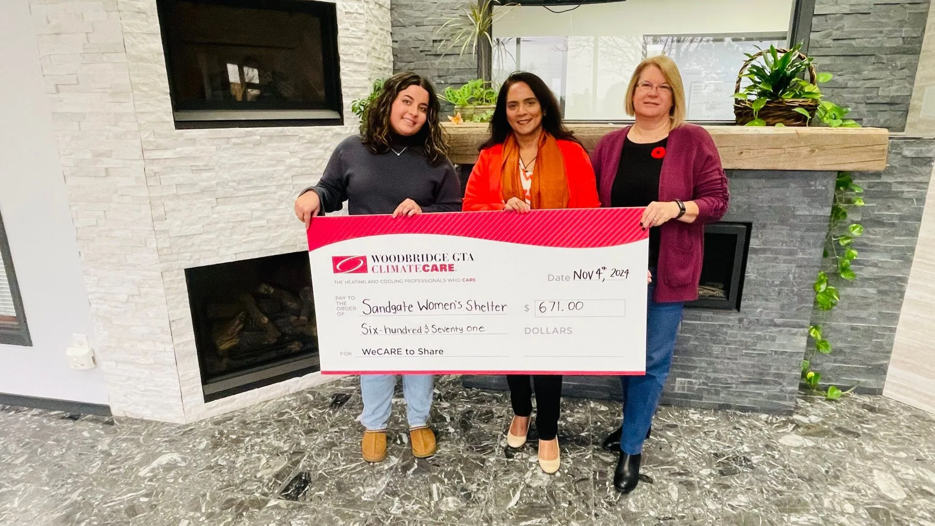 Three women holding a large check for a donation.