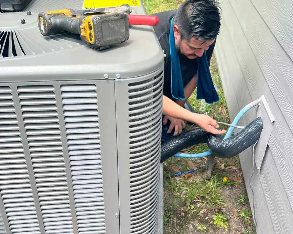 Technician servicing an outdoor air conditioning unit.