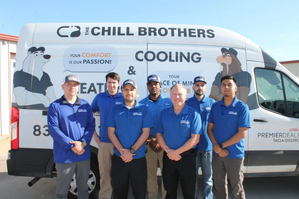 A team of HVAC technicians in front of a service van.
