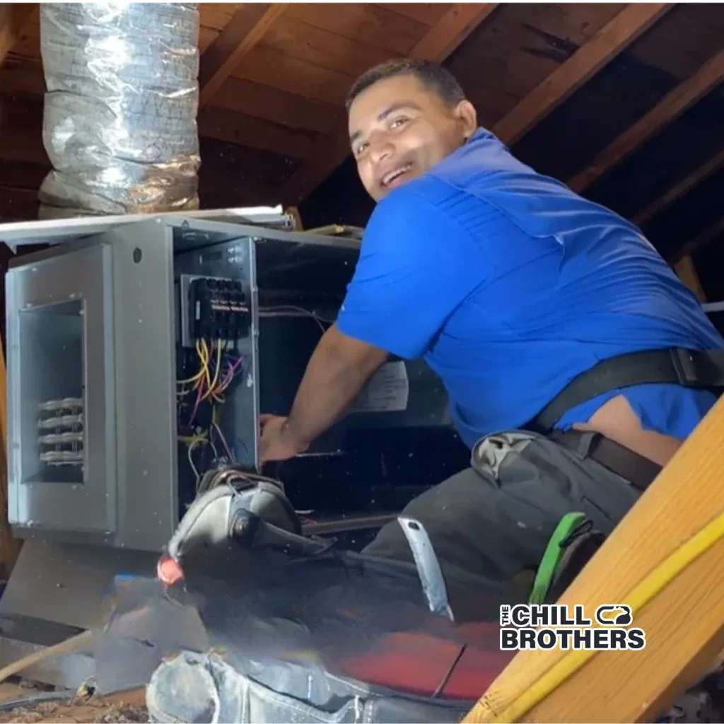 HVAC technician working on an AC unit in an attic.
