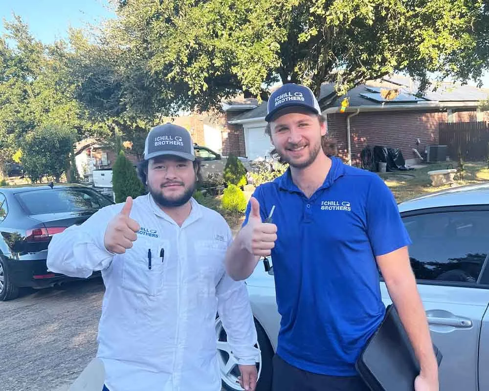 Two HVAC technicians giving a thumbs up outside.