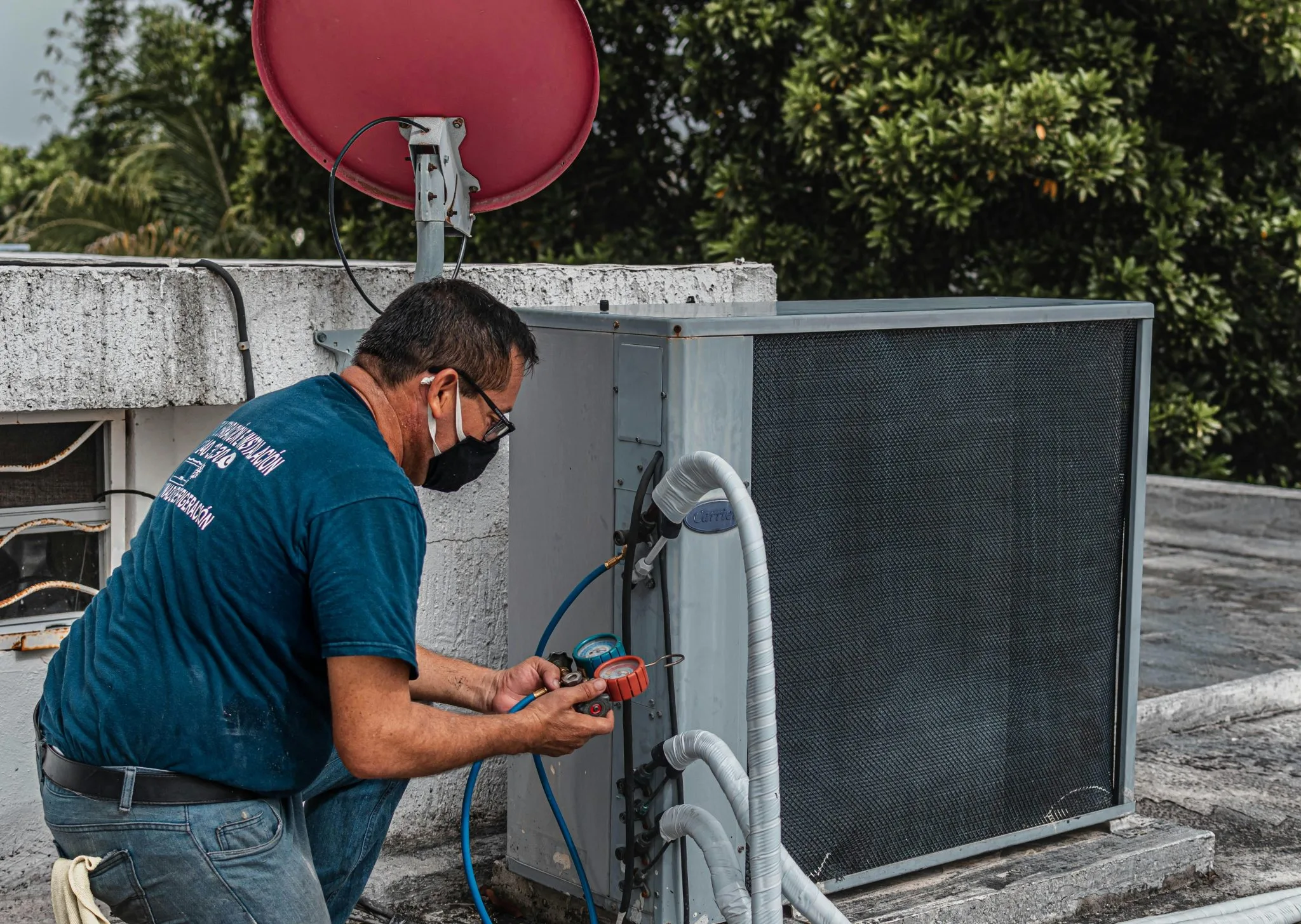 A technician working on an outdoor HVAC unit on the roof.