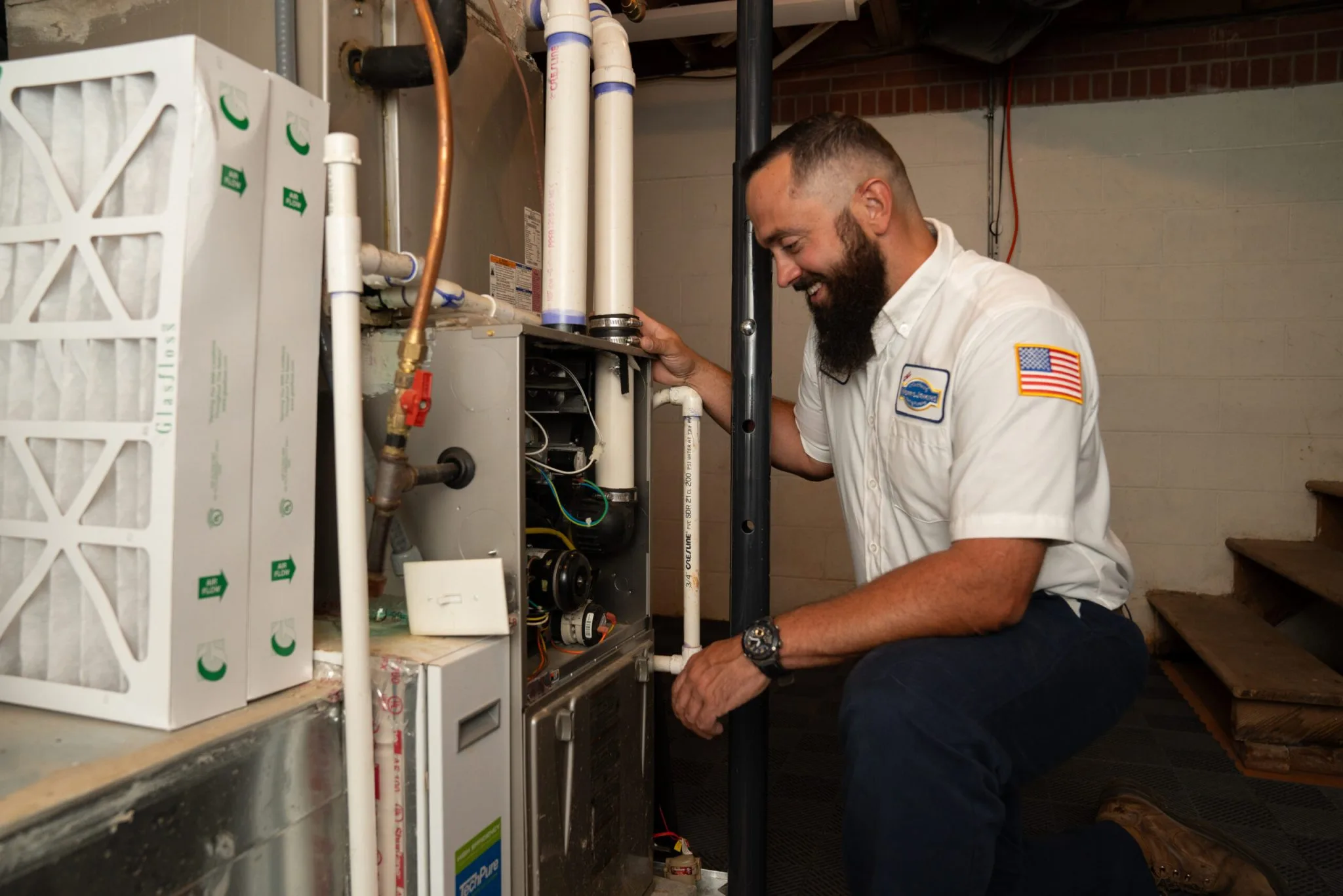 A technician servicing a furnace in a basement.
