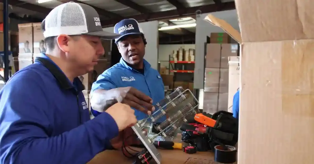 Two HVAC technicians inspecting a heating unit in a warehouse.
