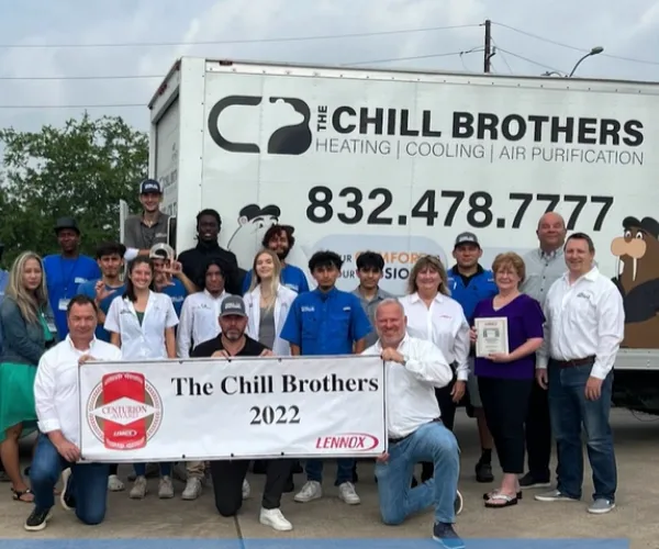 HVAC team posing with a service truck and award banner.