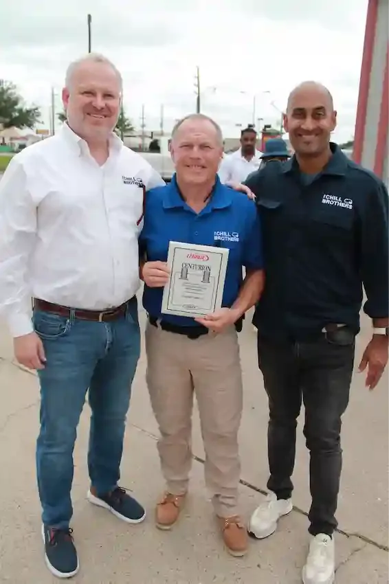Three men celebrating an award outdoors.