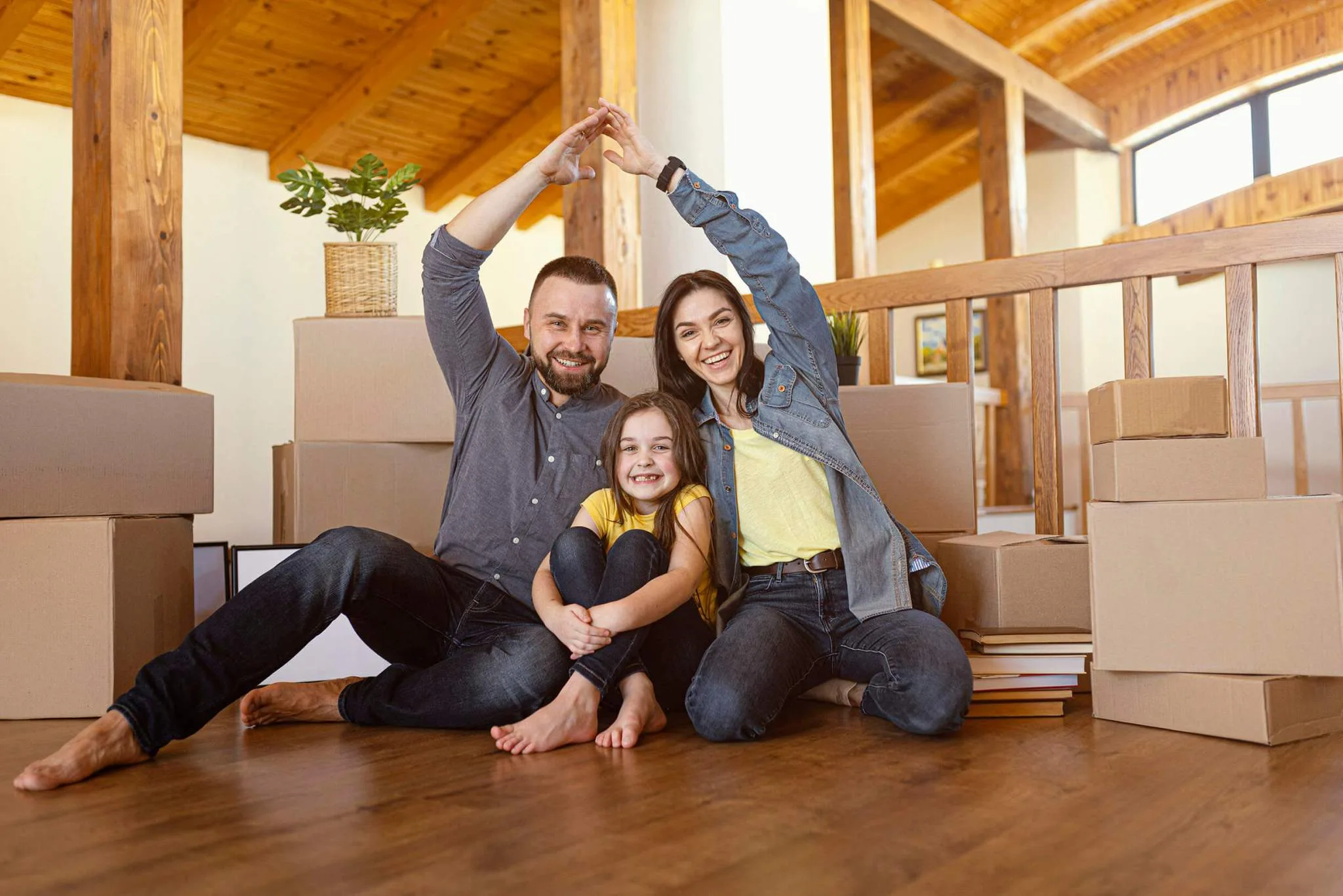 A family making a heart shape with their arms while sitting on the floor.