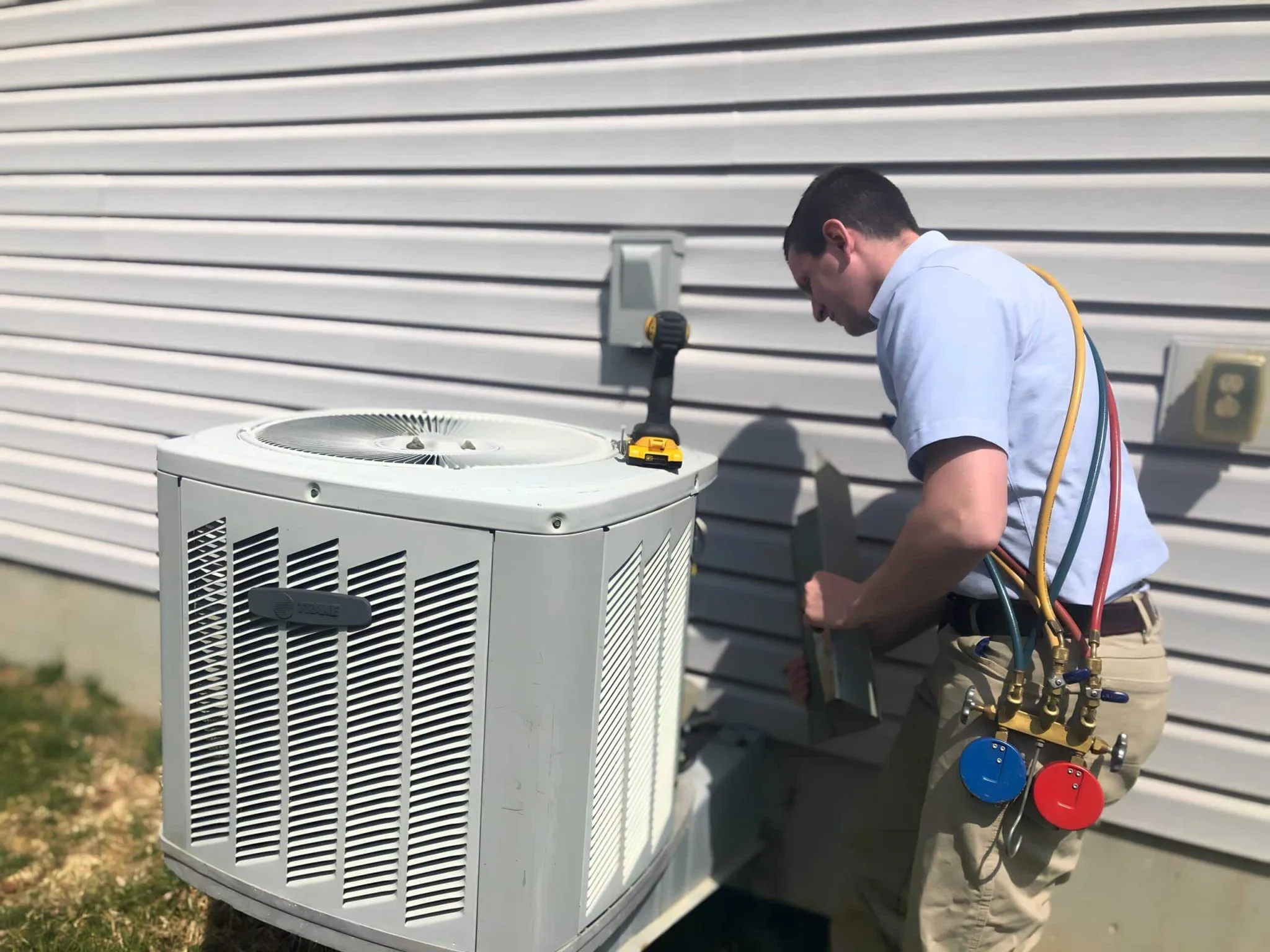 Technician repairing an outdoor air conditioning unit.