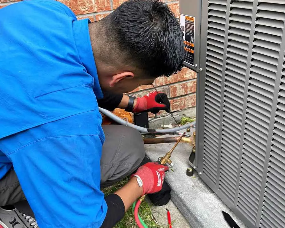 Technician repairing an HVAC system outside a building.