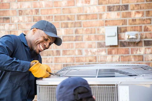 Technician servicing an air conditioning unit outdoors.