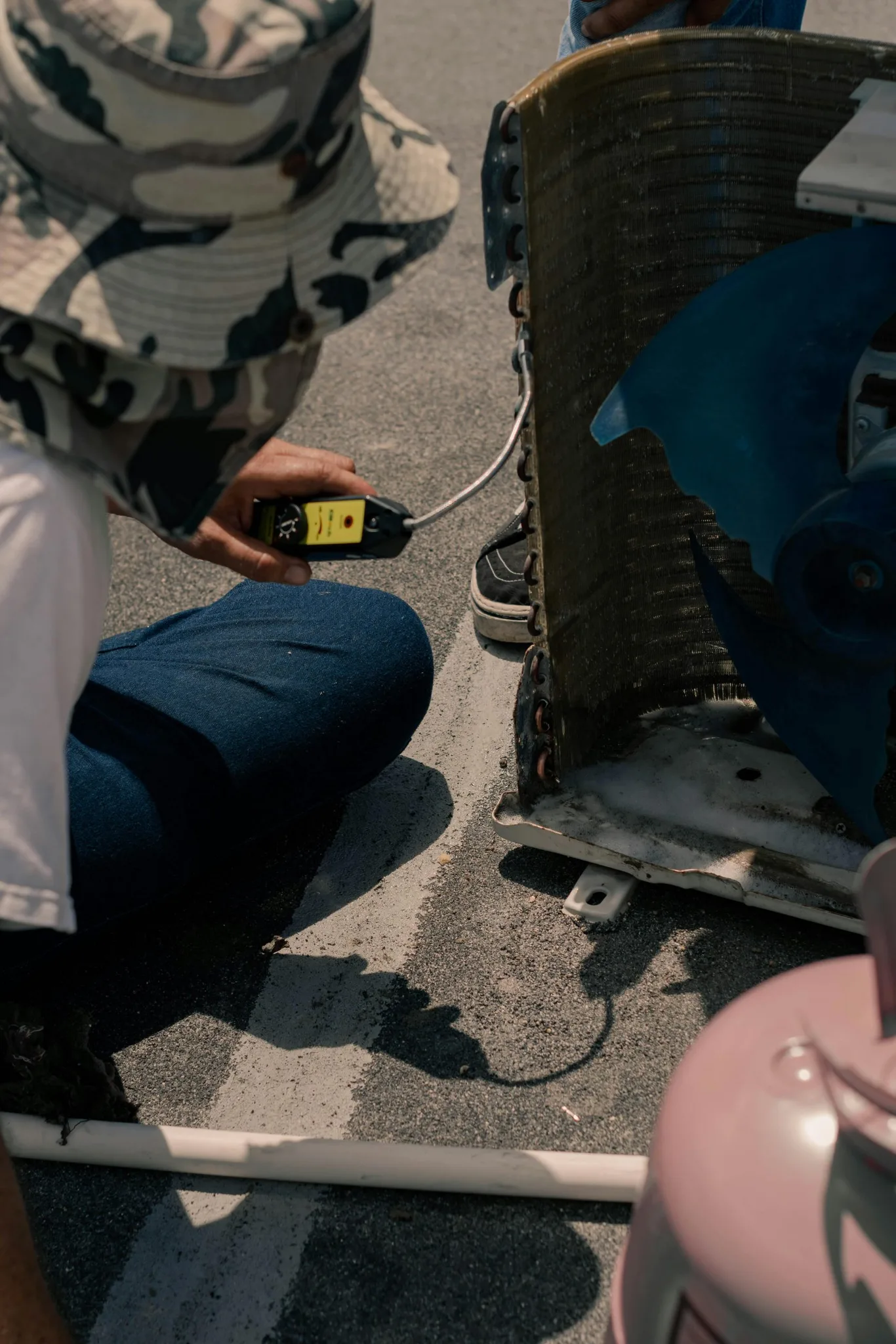 A technician measuring HVAC equipment on a rooftop.