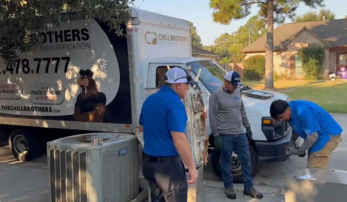 Technicians working on an HVAC unit next to a service vehicle.