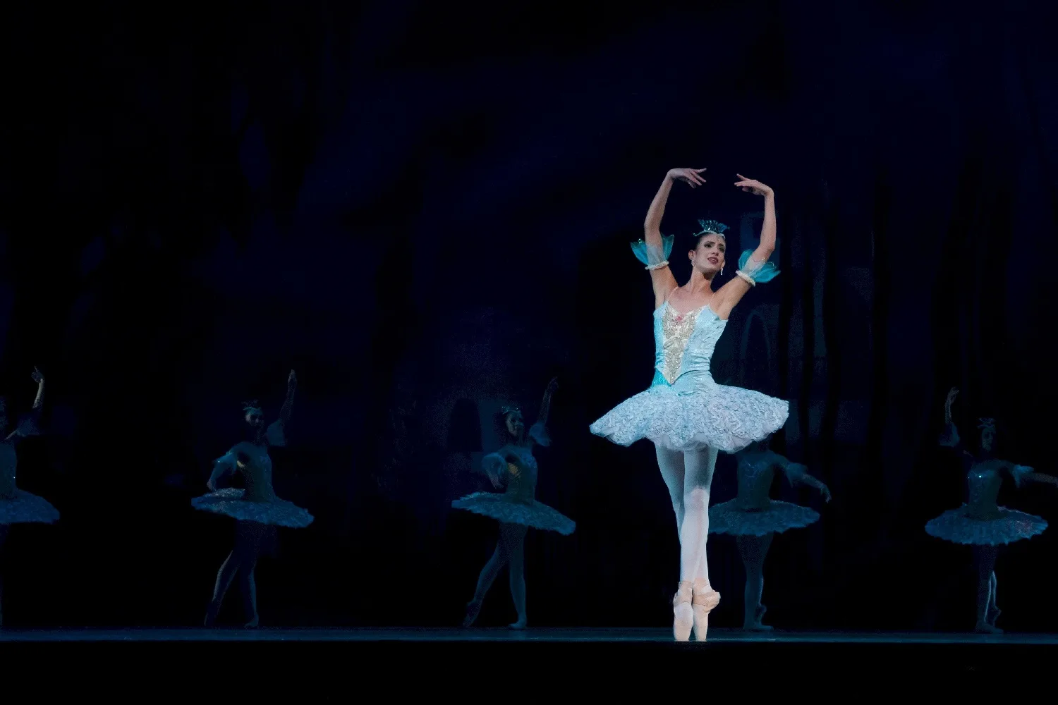 Ballerina performing on stage in a blue tutu.