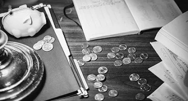 Coins and paperwork scattered on a wooden desk.