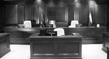 A courtroom setup with dark wood furniture and white chairs.