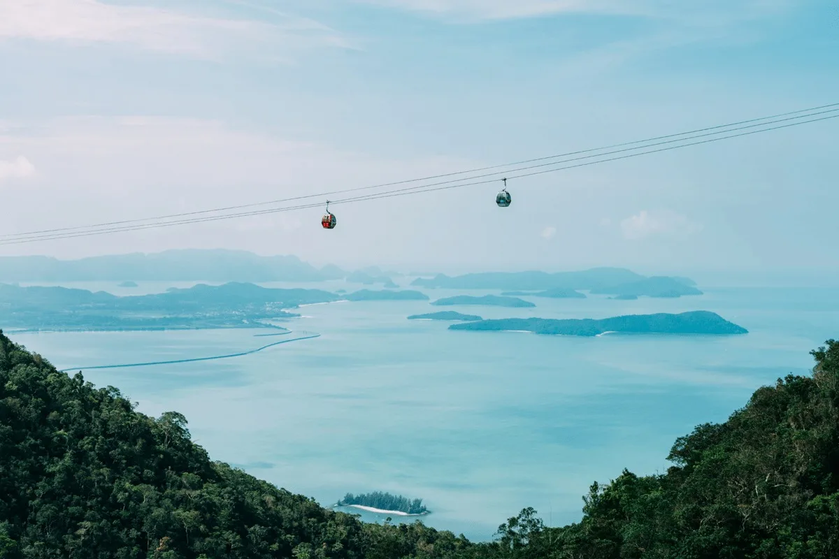 A view of two gondolas over turquoise waters and islands.