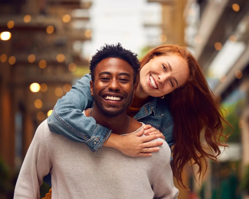 A happy couple smiling outdoors in an urban setting.