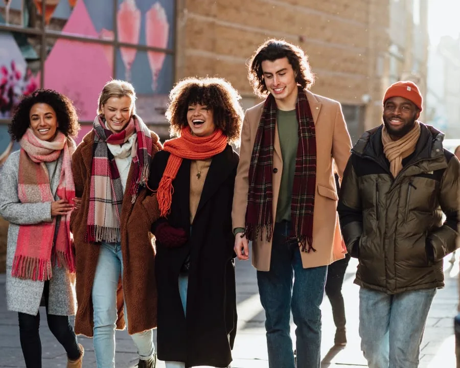 A group of five young adults walking cheerfully in the city.