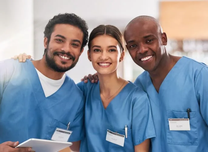 Three dental professionals smiling in a clinic.