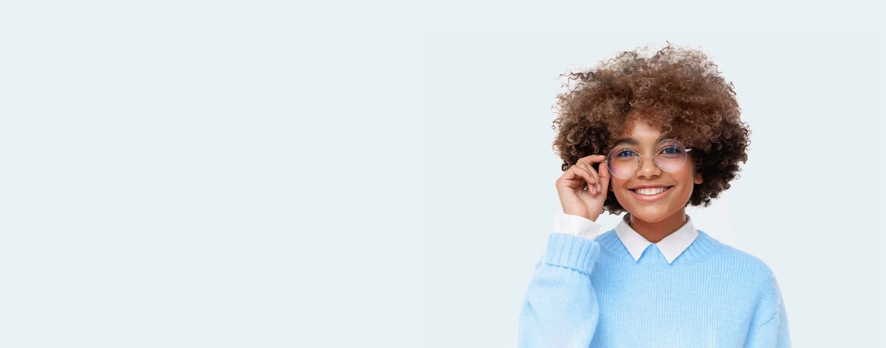 Smiling woman with glasses and curly hair in a blue sweater.