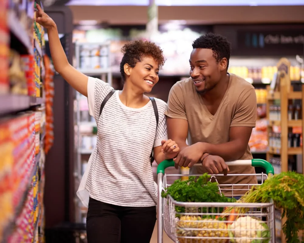 A couple smiling while shopping in a grocery store.
