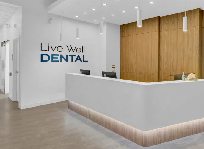 Modern dental reception area with wooden wall and counter.