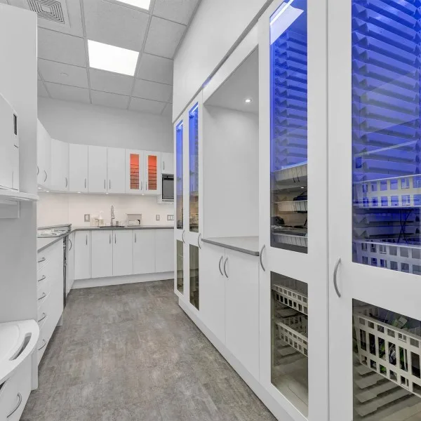 A modern dental clinic interior with white cabinets and blue lighting.