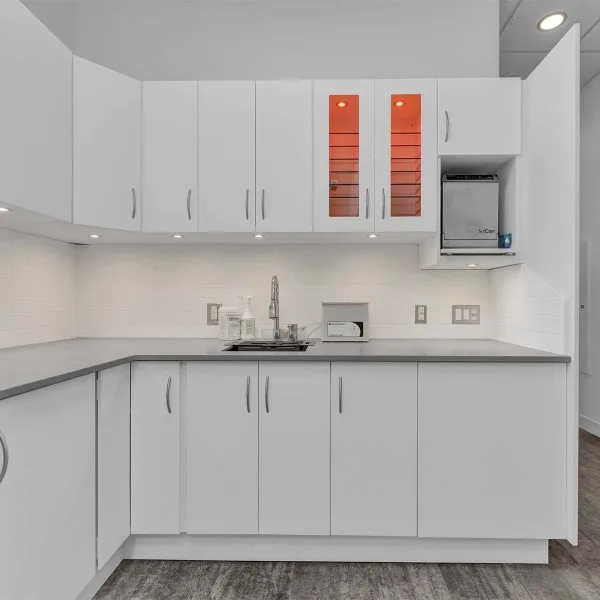A modern dental clinic kitchen with white cabinets and gray countertop.