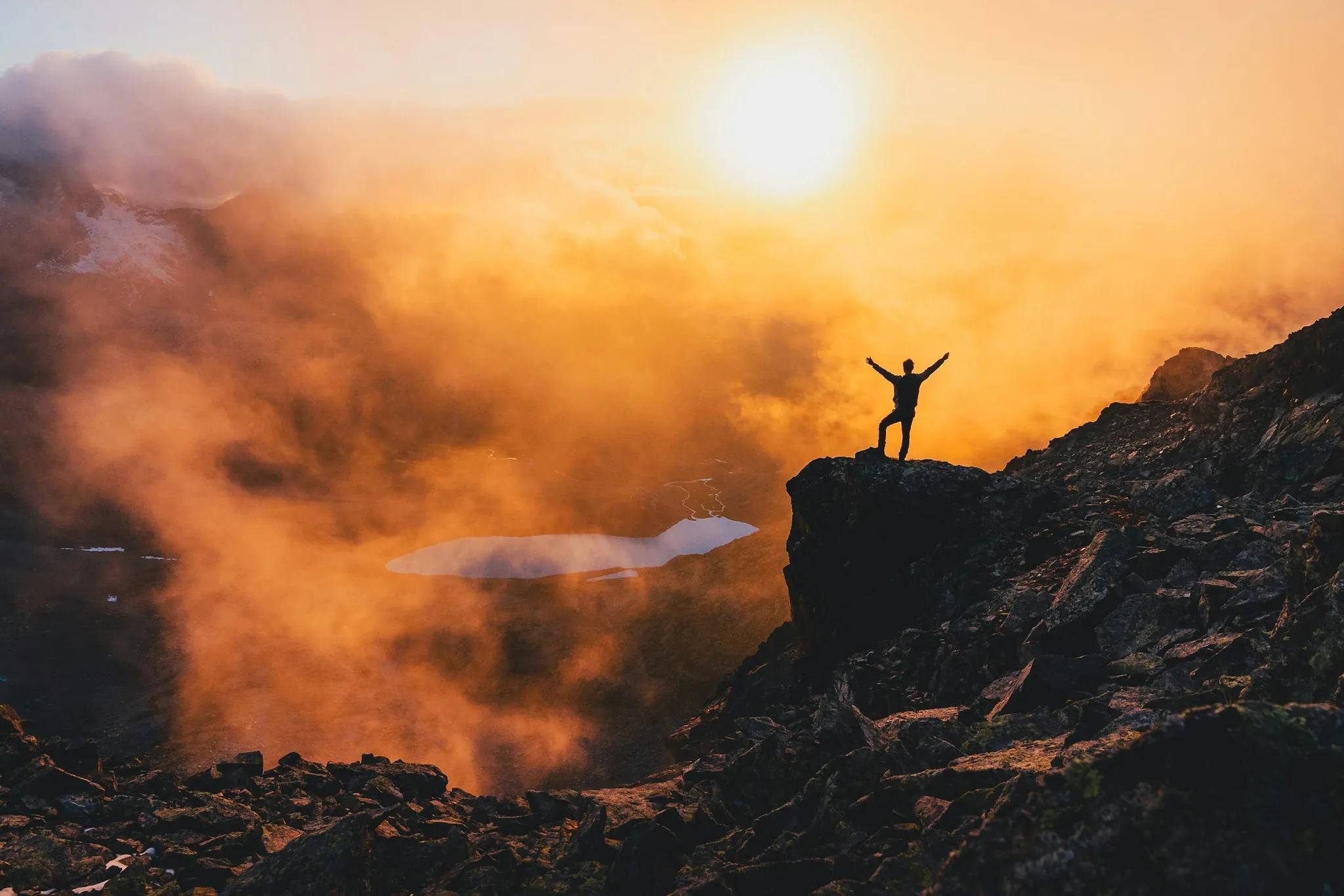 Silhouette of a person on a mountain at sunrise.