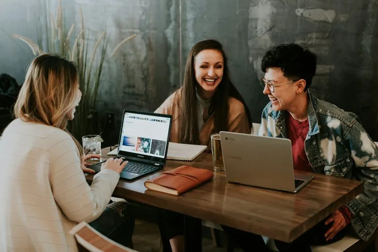 Three people collaborating at a table with laptops.