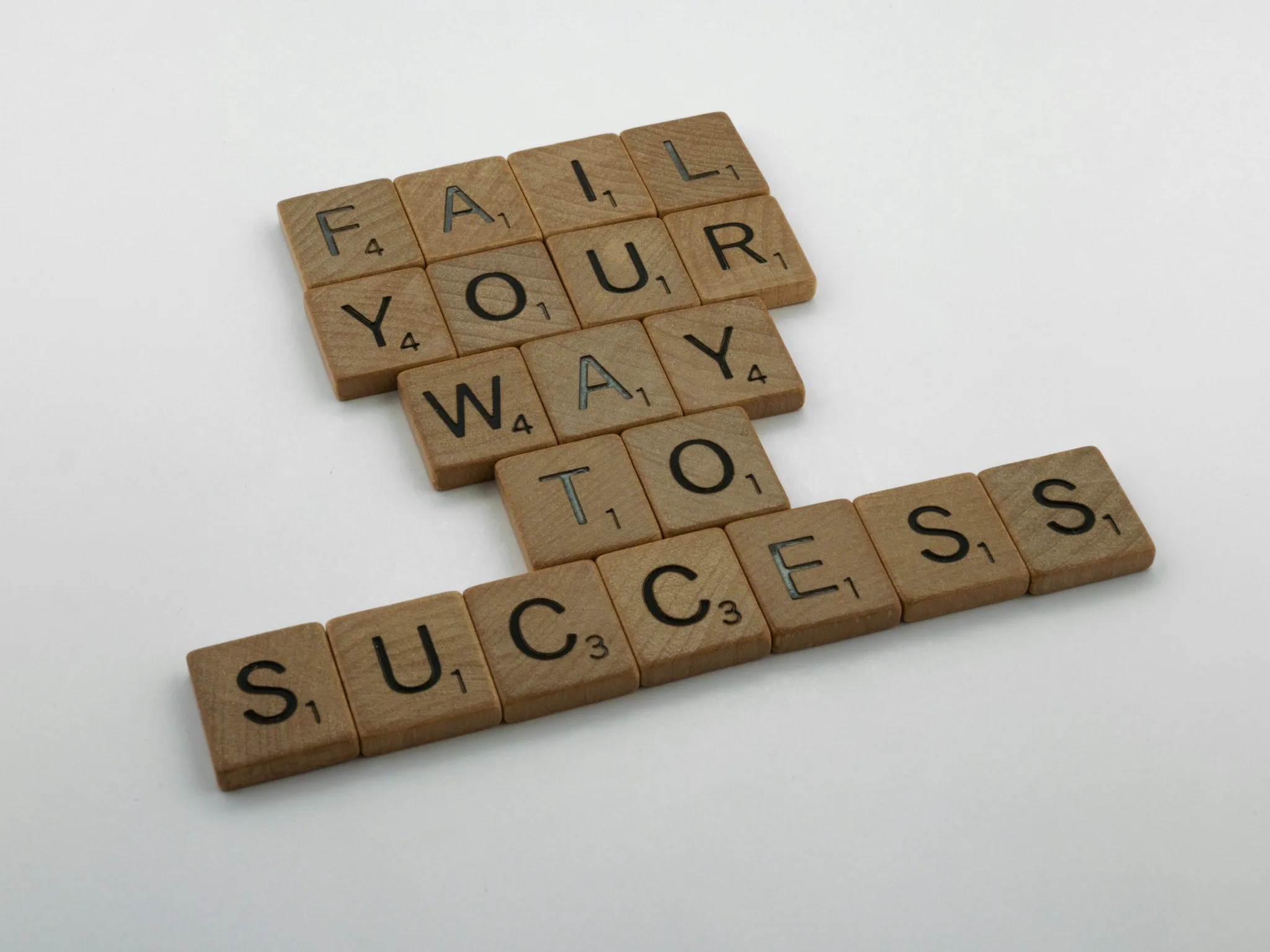 Scrabble tiles forming the phrase 'FAIL YOUR WAY TO SUCCESS'.