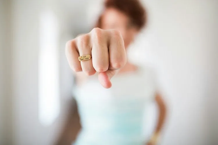 A person raises a fist wearing a gold ring.