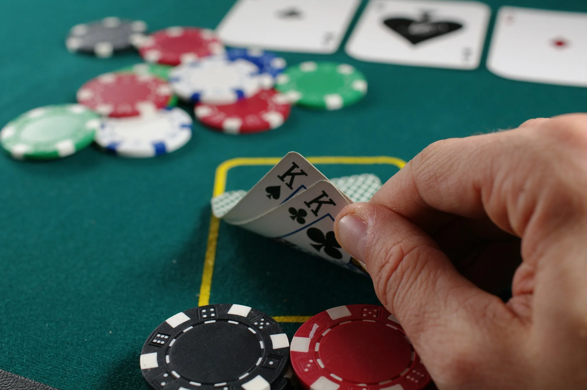 A person holding playing cards and poker chips on a table.