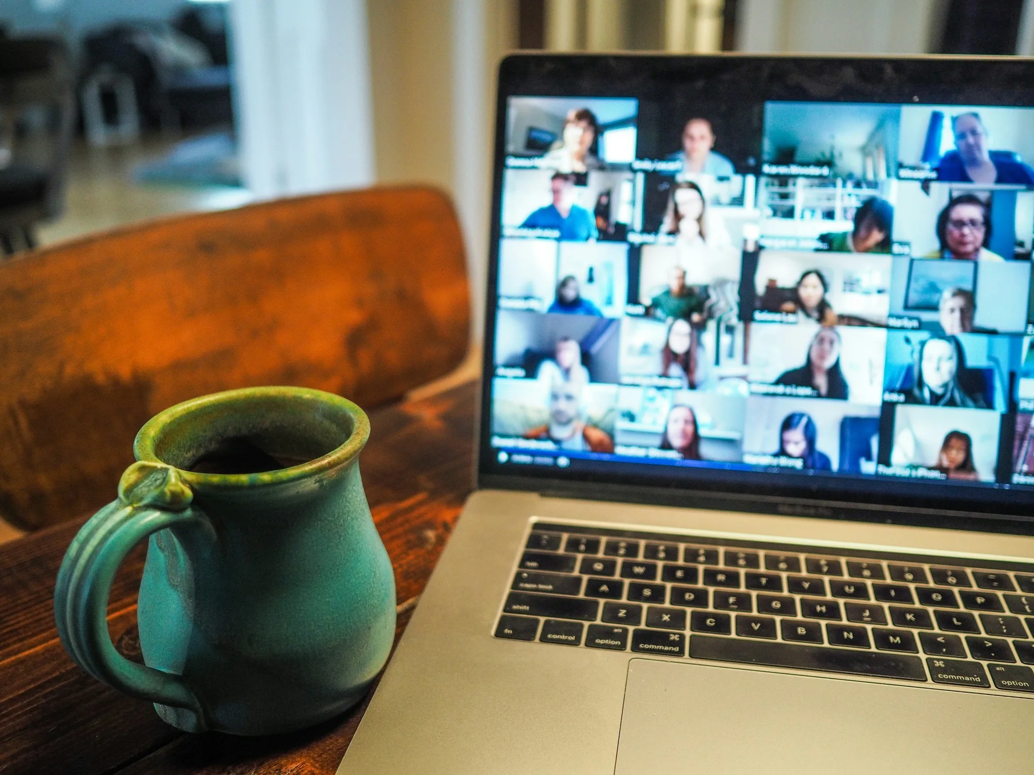 A video conference displayed on a laptop with a coffee mug nearby.