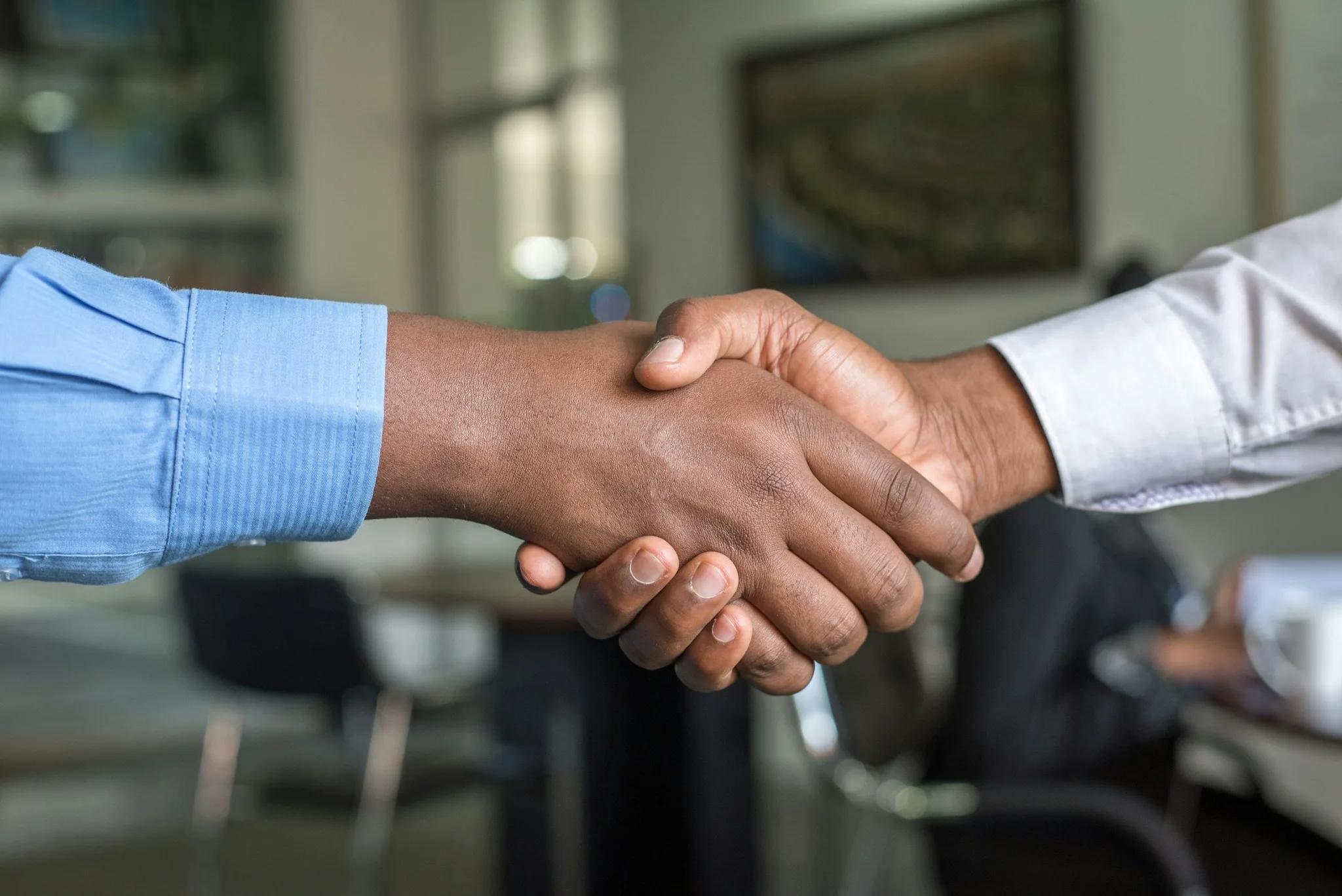 Two hands shaking in an office setting.